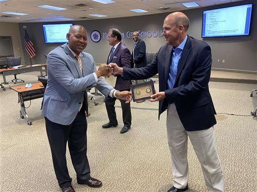 Eric Terrell and Mayor Finley fist bump over commemorative coin 