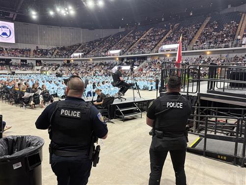 graduates in background with police in foreground